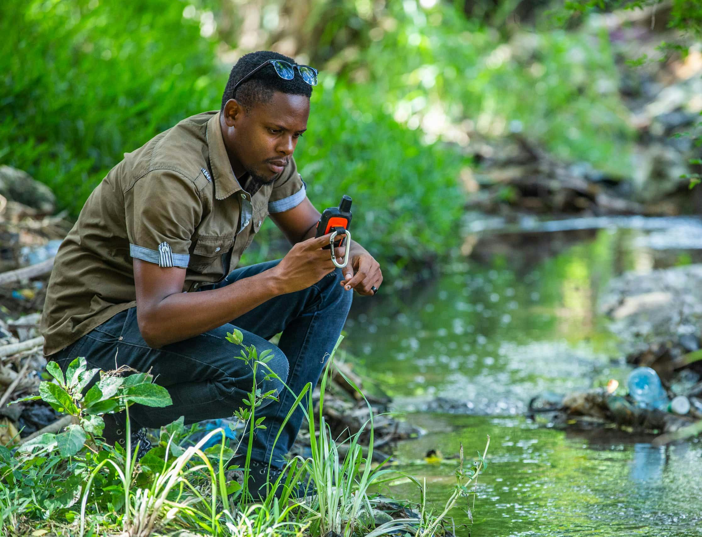 A photo of a GIS expert in the field tracking pollution in rivers that pour out to the Indian Ocean, Tanzania